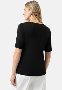 Sort t-shirt med korte ærmer og bred halsudskæring, blød tekstur, løs pasform og minimal syning på ryggen.