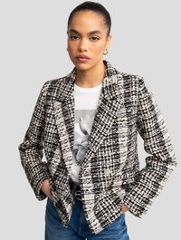 Blazer a quadri in bianco e nero con texture, rever a punta e design doppiopetto. Abbinato a una t-shirt grafica, completato da jeans blu scuri.