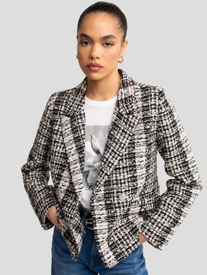 Textured, black and white checked blazer with notched lapels and double-breasted design. Styled over a graphic t-shirt, featuring dark blue jeans.