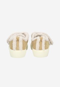Beige mokkasiinit, joissa on pörröinen valkoinen vuori ja teksturoitu takapuoli. Pohja on off-white, ja päällisessä on ainutlaatuinen muotoilu.