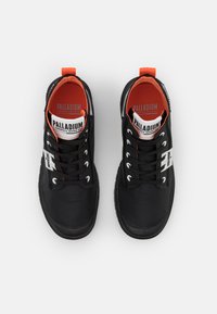 Sneakers in tessuto nero con accenti arancioni, dotati di un design con lacci, punta rotonda e superficie texture. Logo sulla linguetta e sul pannello laterale.