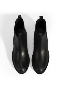 Bottes cheville en cuir noir à finition lisse, avec des panneaux latéraux élastiques et un talon et un bout renforcés. Conçues avec des languettes pour un enfilage facile.