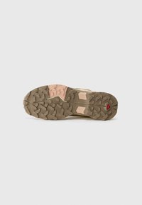 Trail shoe outsole, featuring deep lugs for traction, in dark brown with pink and light tan accents; textured for grip and durability.