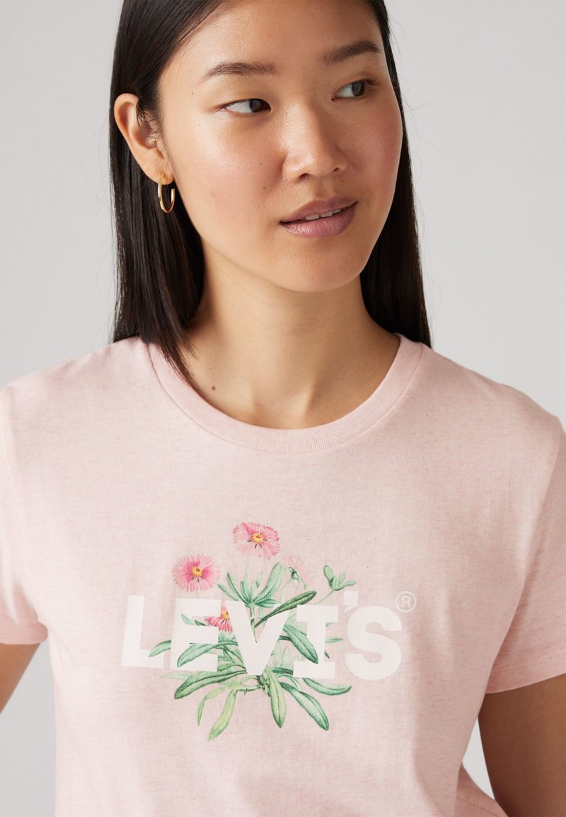 Helles rosa Baumwoll-T-Shirt mit einer botanischen Illustration von Blumen und Blattakzenten, mit dem Text "LEVI'S", der deutlich darunter angezeigt wird.