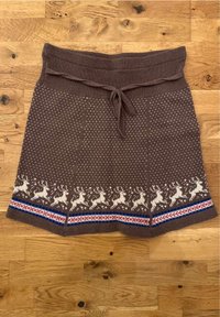 Jupe en tricot marron avec une taille côtelée, ornée d'un motif de rennes blancs le long de l'ourlet et d'accents rayés bleus et rouges.