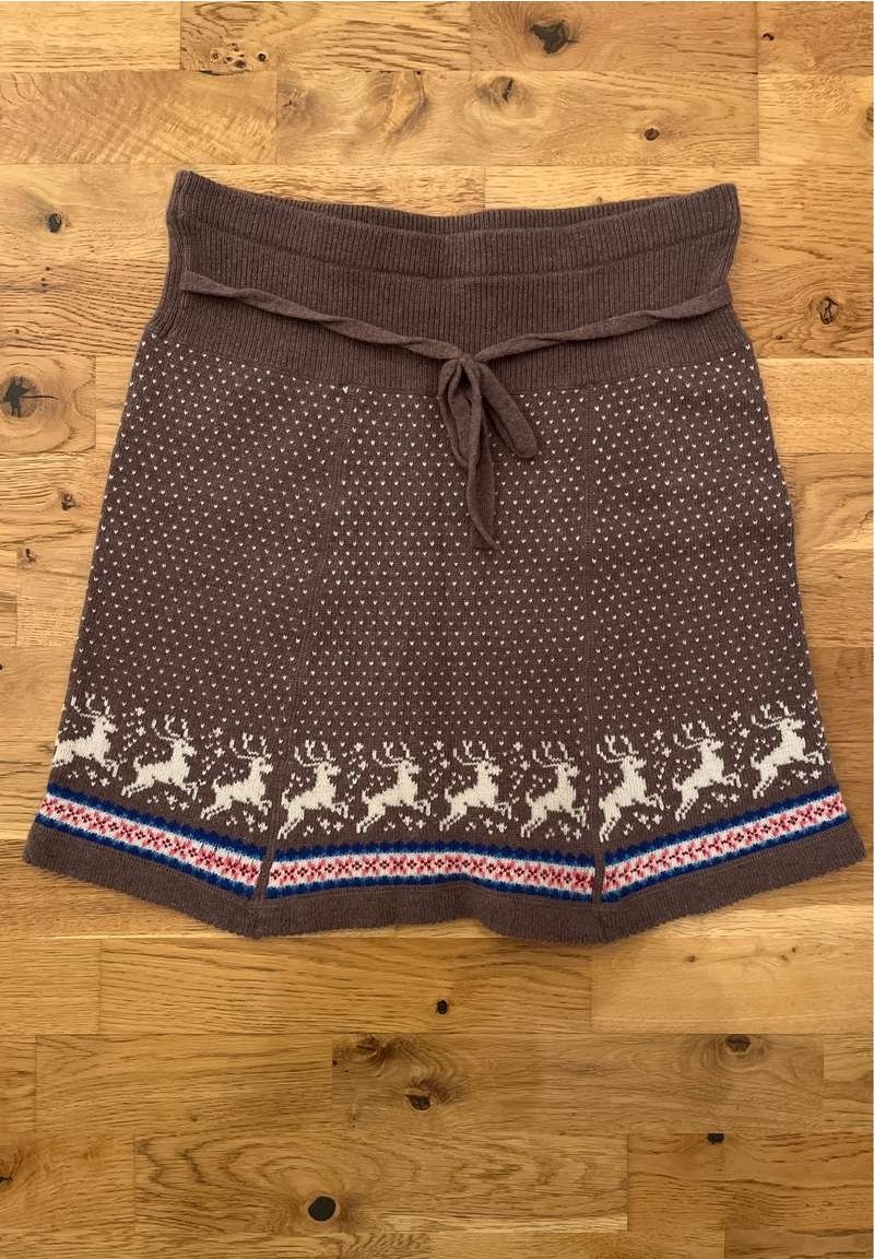 Jupe en tricot marron avec une taille côtelée, ornée d'un motif de rennes blancs le long de l'ourlet et d'accents rayés bleus et rouges.