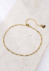 Collar de cadena de oro trenzado con un cierre de langosta y una cadena de extensión, que presenta un pequeño charm en forma de espiral, exhibido sobre una superficie clara.