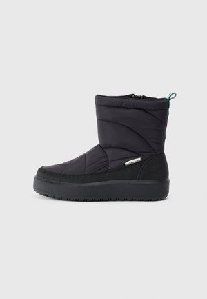 Bottines noires matelassées avec un bout rond, tige en tissu texturé, col rembourré et semelle en caoutchouc épaisse. Fermeture éclair sur le côté et détail de boucle à l'arrière.