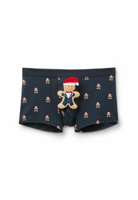 Herrboxer i marinblått, med ett upprepat mönster av pepparkaksmän med röda tomteluvor. Inkluderar en mjuk pepparkaksfigur med tillbehör.