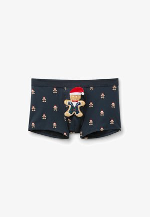 Männer-Boxershorts in Marineblau, mit einem wiederholten Lebkuchenmann-Muster und roten Weihnachtsmützen. Enthält eine kuschelige Lebkuchenfigur mit Zubehör.