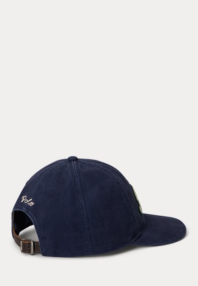 Navy blue baseball cap with adjustable brown leather strap and "Polo" embroidered in white on the back left side.
