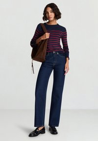 Maglietta a maniche lunghe a righe blu navy e rosse, pantaloni a gamba larga in denim scuro a vita alta, borsa in suede marrone, mocassini neri, design minimalista.