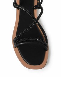 Sorte flade sandaler med krydsede stropper i flettet tekstur. Firkantet tådesign og en kontrastfarvet tan sål.