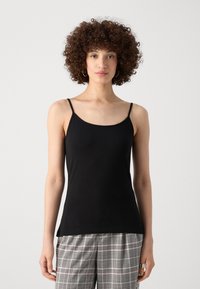 Schwarzes Top mit dünnen Trägern, weicher Textur, tailliertem Design und rundem Ausschnitt, kombiniert mit gemusterten Karohosen.