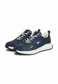 Granatowe buty sportowe z białymi sznurówkami, jasnymi podeszwami i teksturowaną cholewką z małym czerwonym i niebieskim logo.
