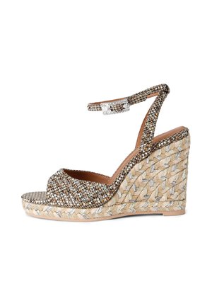 Sandaal met sleehak van gevlochten espadrille, glinsterende strassbandjes en een enkelriempje met gesp op een witte achtergrond.