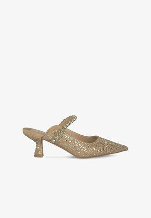 Beige mesh slingback hak met een spitse neus, versierd met geometrische uitsparingen en strassaccenten; heeft een lage, uitlopende hak.