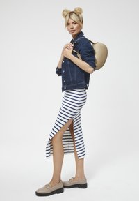 Spijkerjack, gestreepte midi-rok met zijsplit en beige loafers. De outfit heeft een casual ontwerp met contrasterende kleuren.