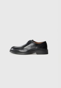 Black leather dress shoe with a rounded toe, smooth surface, lace accents, and a low, textured rubber sole. Clean lines and minimal design.