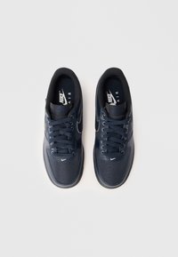 Baskets Nike Air de couleur bleu marine, avec une tige en toile et synthétique, bout rond, design à lacets, et accents de logo blancs.