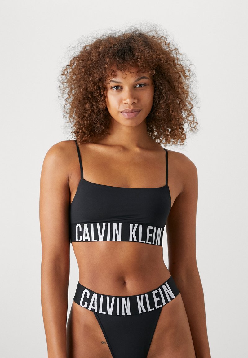 Schwarzes Bikini-Set mit einem Bralette mit dünnen Trägern und Logoband, kombiniert mit einem hochtaillierten Tanga-Bottom mit passendem Logodetail.