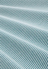 Turkusowo-biała tkanina w paski o gładkiej teksturze, prezentująca ukośne linie i subtelne wzory fal wzdłuż powierzchni.