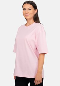 T-shirt oversize rose en coton léger, avec des manches courtes, un col rond et une coupe décontractée.