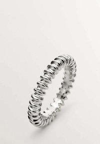 Anillo elástico de plata con cuentas redondeadas y texturizadas, creando un diseño suave y flexible. Estilo simple y minimalista.