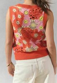 Hihaton neuleliivi, jossa on kukkakuvioinen virkkaus punaisena, vaaleanpunaisena ja keltaisena. Viimeistelty ribbaatulla oranssilla helmalla ja takatiedoilla.