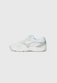 Baskets blanches avec une tige en mesh, accents argentés et un talon vert clair. Elles possèdent une semelle rembourrée et des lacets dans un teal contrasté.