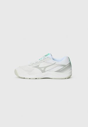 Sapatilhas brancas de desporto com parte superior em malha, detalhes em prata e salto verde claro. Apresentam uma sola almofadada e atacadores em teal contrastante.