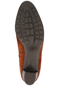 Ruskea mokkanahkainen korkokenkä, jossa on teksturoitu kumipohja, pyöristetty kärki ja hienovaraiset ompeluyksityiskohdat sivuilla.