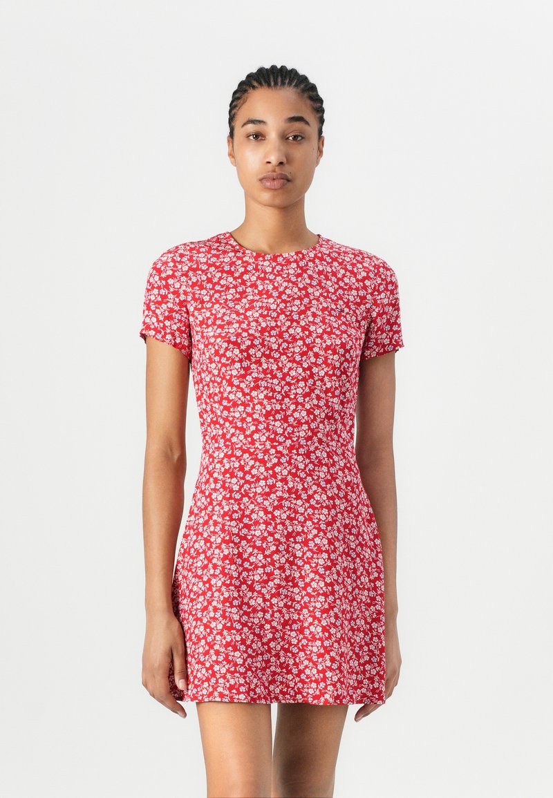 Robe en coton rouge à manches courtes, silhouette ajustée, motif floral, décolleté rond et texture lisse. Pas de fermetures ni d'ornements visibles.