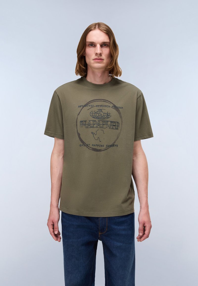 Olivengrøn bomulds-T-shirt med en sort grafisk logo, der læser "NAPAPIJRI" med cirkulære accenter og tekst, rund halsudskæring og korte ærmer.