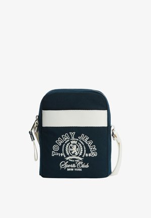 Borsa a tracolla Tommy Jeans blu navy con striscia orizzontale bianca, logo ricamato e tracolla bianca regolabile.