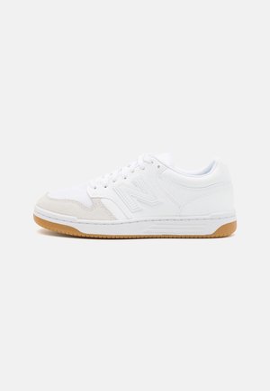 Hvid lavtop sneakers med beige tåhætte, hvide snørebånd, logo på siden og brun gummisål mod ensfarvet baggrund.
