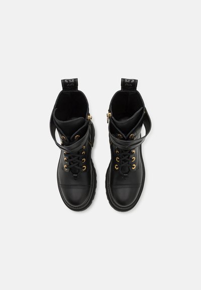 Svarta läderankelboots med guldfärgad hårdvara, snörning fram, vadderad krage och dragögla. Har en slät textur och en kraftig gummisula.