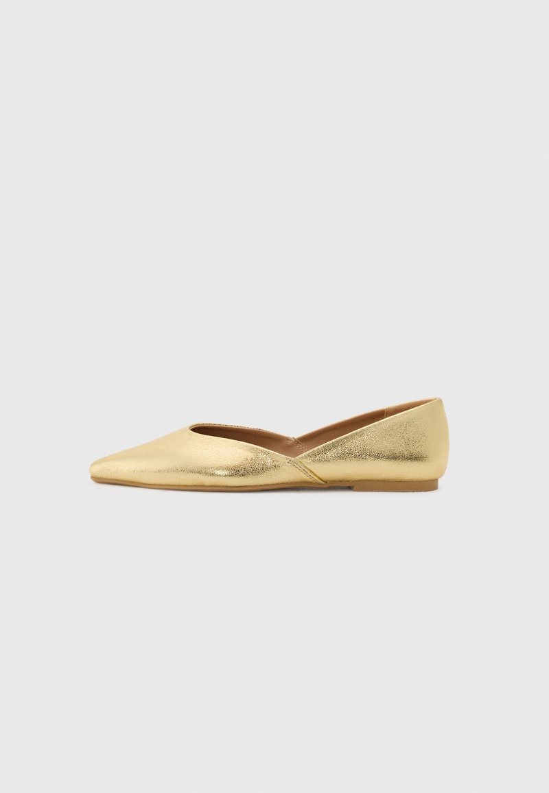Chaussure plate en or métallique brillant avec un bout pointu et des côtés bas sur un fond blanc uni.