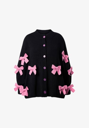 Cardigan en tricot noir orné de sept nœuds en tissu rose, avec un col rond et des boutons violets sur le devant. Texture douce, coupe décontractée.