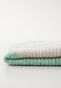 Knit blanket with a textured pattern, featuring light green, cream, and blue stripes, creating a layered appearance. Soft wool material.