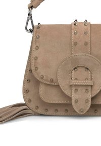 Beżowa zamszowa torebka na ramię z dwoma kieszeniami, srebrnymi ćwiekami i okrągłym zapięciem. Posiada odpinany pasek oraz detal w postaci frędzli.