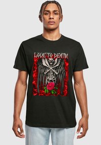 Svart t-skjorte med grafisk design som viser et skjelett, vinger, en rose, og teksten "LOVE TO DEATH" i sølv. Bakgrunn i røde flammer.