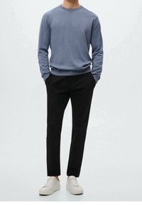 Pull à col rond manches longues bleu clair, associé à un pantalon noir slim et des baskets blanches. Le tissu semble lisse et décontracté.