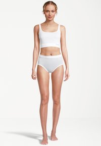 Hvid, sømløs croptop og højtaljede trusser vist på en model, lavet af blødt bomuld med en glat tekstur. Enkel design uden mønstre.