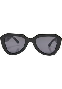 Ochelari de soare negri, cu formă cat-eye, finisaj mat, design unghiular și lentile gri închis. Au rame groase și temple subțiri. Marcati "Urban Classics."