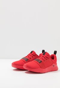 Baskets de sport rouges en maille respirante, avec une tige texturée, des accents noirs et un col rembourré pour le confort.