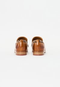 Pantofi din piele de culoare tan, cu o finisare netedă, având accente de imprimeu leopard pe călcâi și pe lateral, și o talpă din lemn cu un toc ușor.