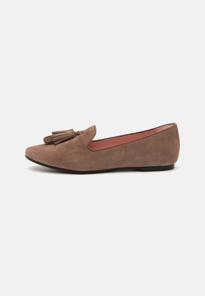 Mocassin plat en daim marron avec bout arrondi et double pompon sur le dessus, doté d'un petit talon noir et d'une doublure intérieure rose.
