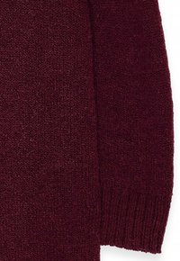 Burgundia lõngaga kootud sviiter, millel on tekstuurne viimistlus, sooniksed mansetid ja lõdvestatud lõige koos peenete kiuliste detailidega.