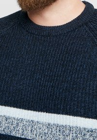 Maglione a maglia blu navy con finitura testurizzata, caratterizzato da strisce orizzontali azzurro chiaro sul petto e un collo a costine.